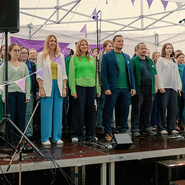 Popchor Spandau singt auf Bühne, Mitglieder sind in grün und blau gekleidet