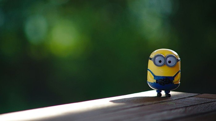 Ein Minion steht vor einem grünen Hintergrund.