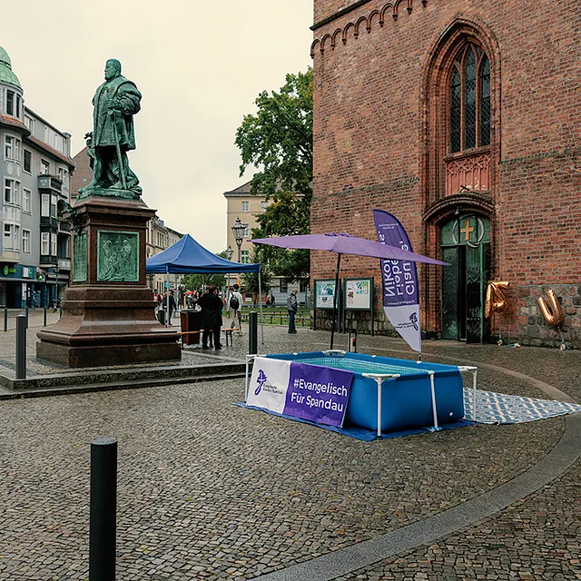 Wasserbecken, Schirm und Beachflag mit Kirchenkreis-Logo vor St. Nikolai