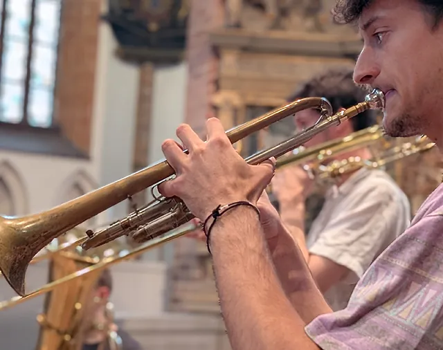 Junge Männer, die Blasinstrumente spielen u.a. Trompete