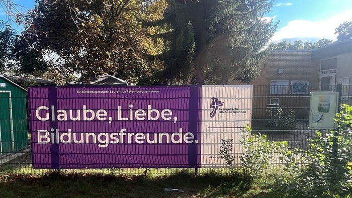 Lila Banner am Zaun: Glaube, Liebe, Bildungsfreunde