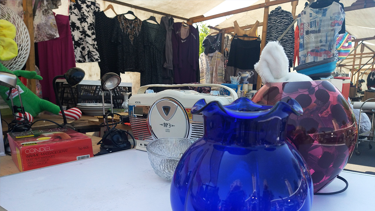 Trödelmarkt mit Vasen, Kleidung, Lampen und anderen Dingen