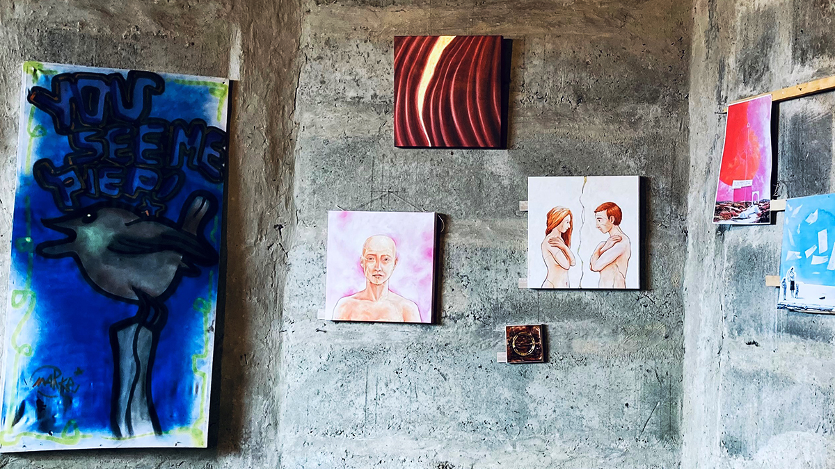Ausstellung von Gemälden auf einer Betonwand, u.a. ein Vogel mit dem Spruch "You see me"