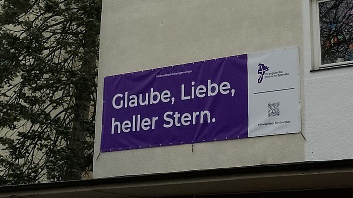 Lila Banner am Gebäude: Glaube, Liebe, heller Stern.