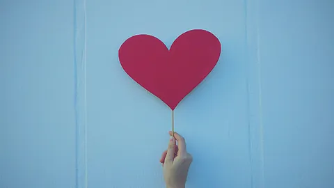 Rotes Herz am Stab gehalten von einer Hand
