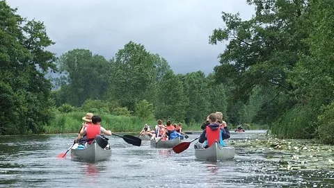 Menschen paddeln mit Kanus auf einem Fluss