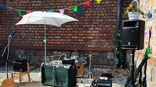 Bandequipment, Sonnenschirm, Wimpelkette vor Backsteinmauer