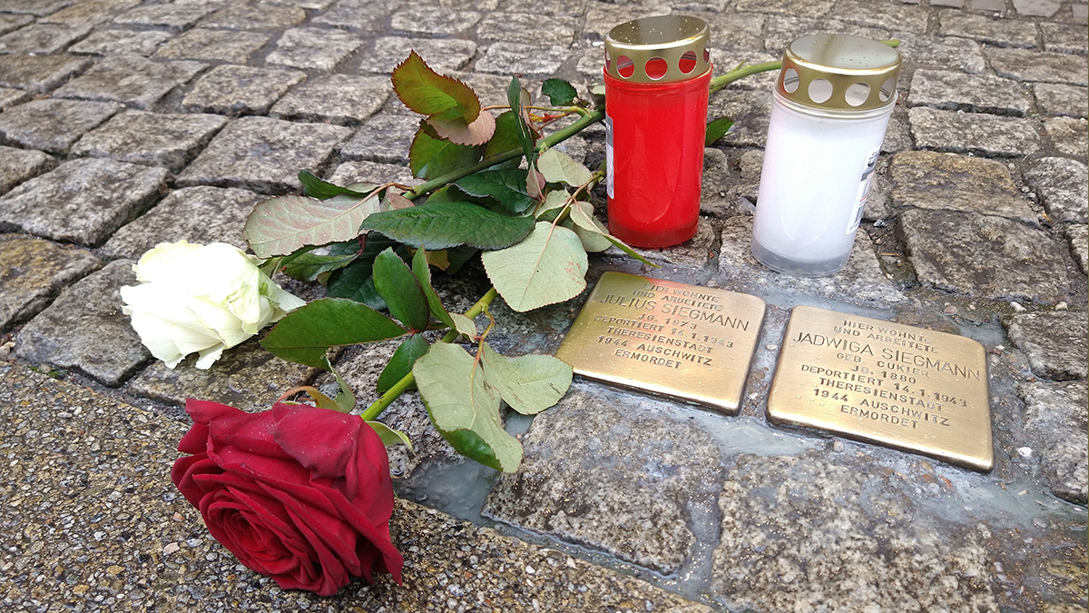 Symbolbild: Stolpersteine mit Rose und Grablicht