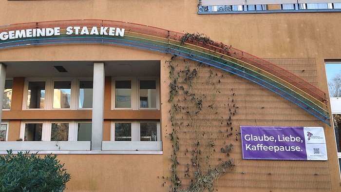 Lila Banner am Gebäude: Glaube, Liebe, Kaffeepause.