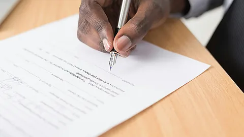 Eine Person füllt ein Dokument mit einem Füller aus.