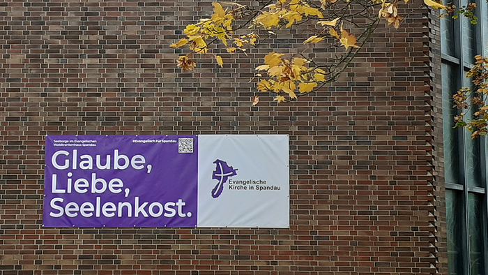 Lila Banner am Gebäude: Glaube, Liebe, Seelenkost.