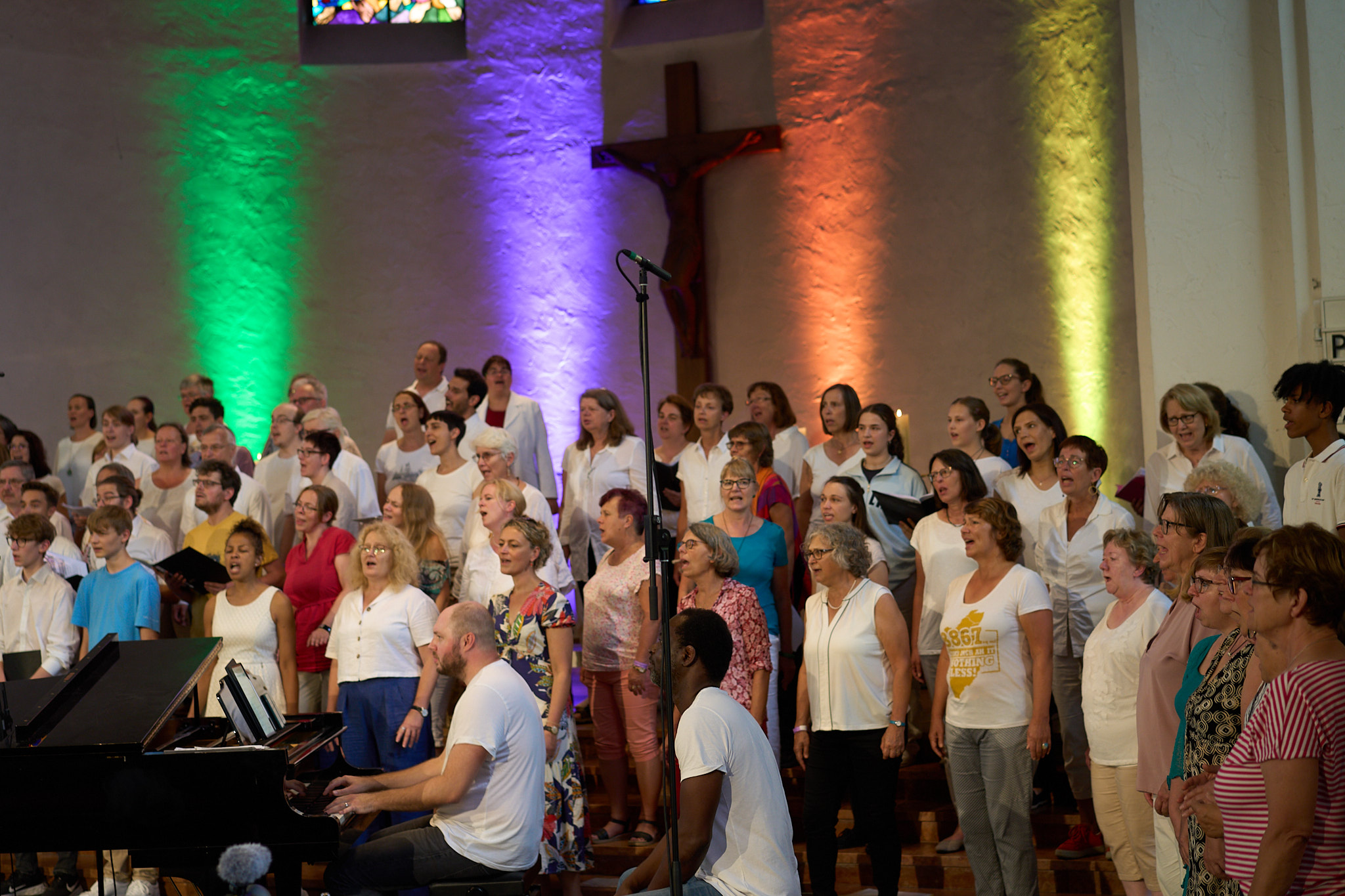 Chor singt vor einer bunt angestrahlten Wand
