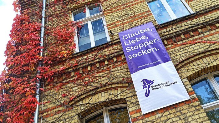 Lila Banner hängt am Gebäude: Glaube, Liebe, Stoppersocken