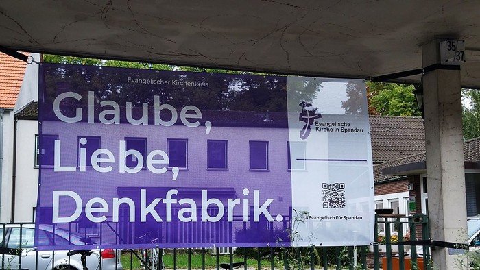 Lila Banner am Zaun: Glaube, Liebe, Denkfabrik