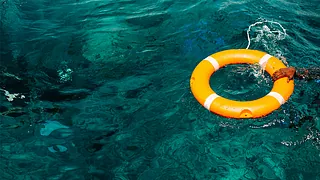 Hand am Rettungsring im Meer