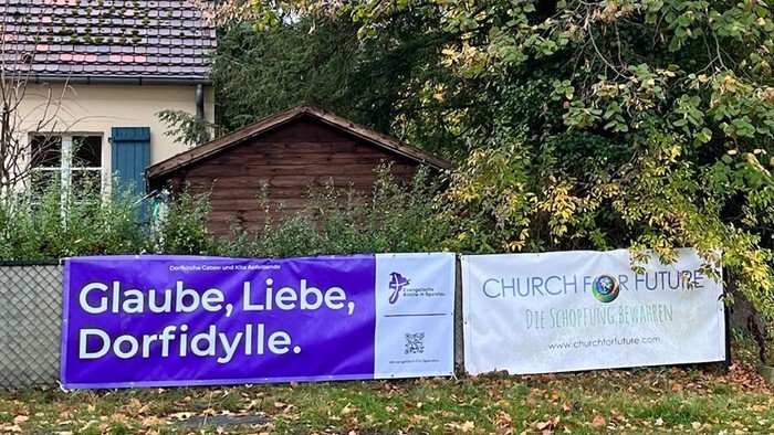 Lila Banner am Zaun: Glaube, Liebe, Dorfidylle.