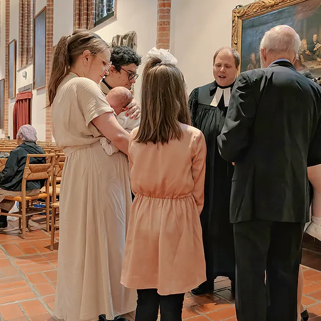 Familie mit Baby und Pfarrer am Seitenaltar