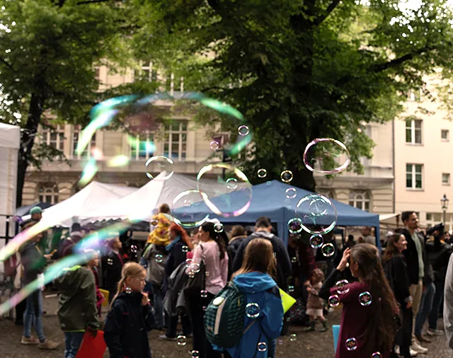 Seifenblasen auf dem Tauffest mit vielen Menschen, Bühne und Pavillons