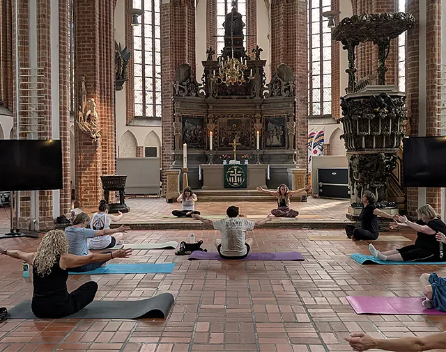 Personen auf Matten beim Yoga in der Kirche