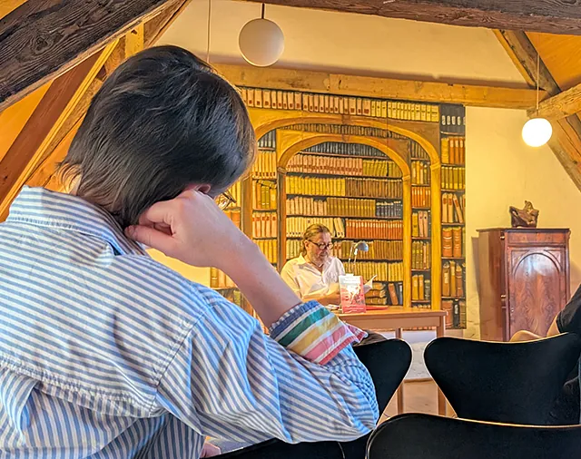 Autorenlesung vor aufgemalter Bibliothek unterem Dach, Zuhörer:innen