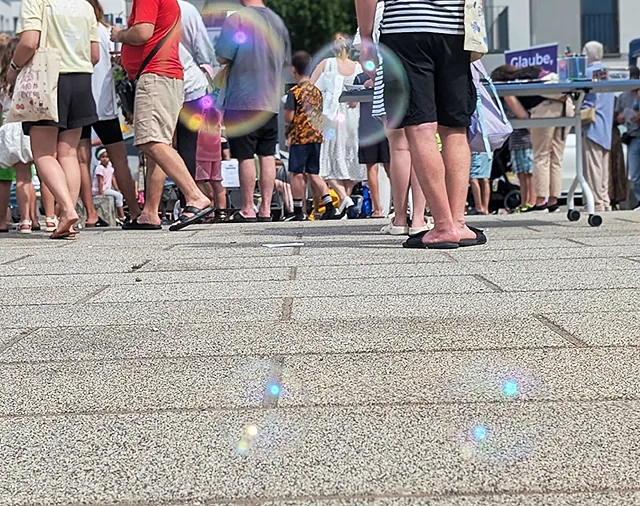 Froschperspektive: Leute in Sommersachen stehen auf Platz, Seifenblasen schweben über dem Boden