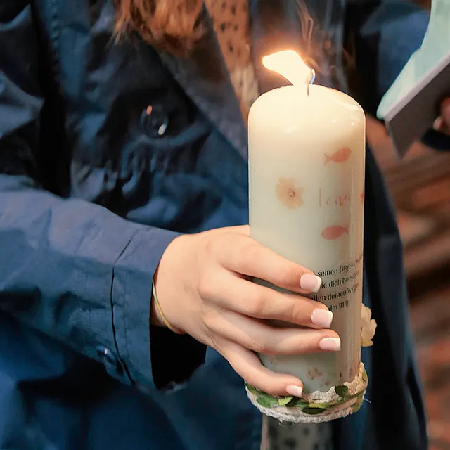 Person hält brennende Taufkerze