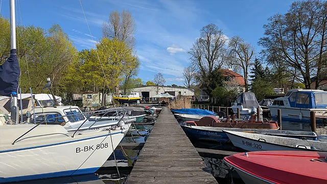 Christophorus-Hafen: Steg mit angelegten Booten, im Hintergrund eine Halle, Villa und Bäume