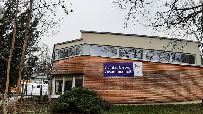 Außenansicht der Kita mit Banner "Glaube, Liebe, Zusammenhalt"