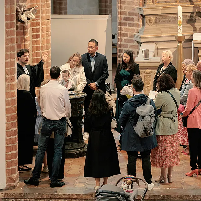 Taufgesellschaft steht um Taufbecken vor Altar in St. Nikolai