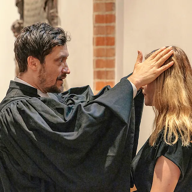 Pfarrer hält seine Hände zum Segen über eine Frau