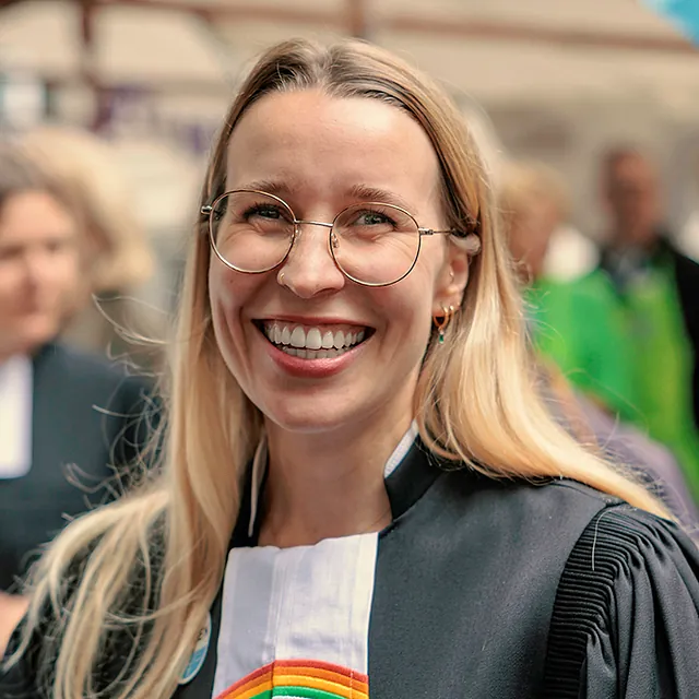 Lächelnde Pfarrerin mit Regenbogenbeffchen